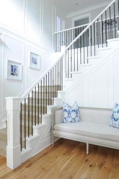 there is a white bench with blue pillows on it in front of the banister