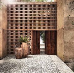 two vases sitting on the ground in front of a wooden structure with latticed doors