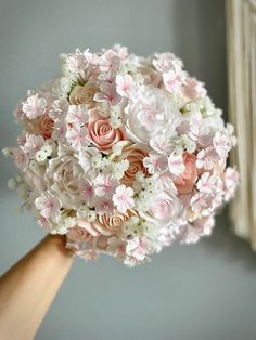 a bridal bouquet being held by someone's hand