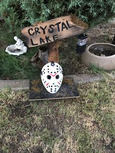 a sign that says crystal lake with a hockey mask on it next to some plants