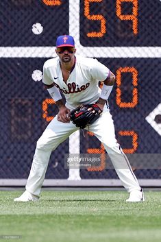 a baseball player standing on the field with his glove in hand and numbers behind him