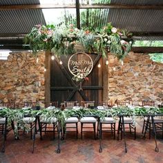 an outdoor venue with tables and chairs set up in front of a barn door decorated with greenery