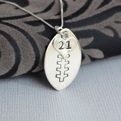 a silver necklace with the number 21 on it and a heart shaped charm hanging from it