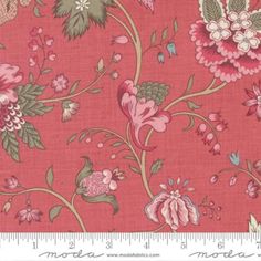 a pink flowered fabric with green leaves and flowers on the side, in front of a ruler