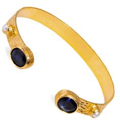 Experience timeless elegance with the Cleopatra Sapphire & Pearl Adjustable Gold Cuff Bracelet. This stunning cuff bracelet, plated in 24k gold on brass, showcases beautiful sapphire stones that come together in perfect harmony. Small pearl accents adorn the bracelet, adding a touch of sophistication and enhancing its authentic, regal charm. Designed to bring both style and elegance to any look, this adjustable cuff bracelet is the perfect statement piece. Details Sapphire stone Crafted with high-quality brass and plated with 24k gold for a luxurious finish. Adjustable size Avoid contact with chemicals, makeup, parfume. Do not use dips or abrasive cleaners on bracelet. To clean and brighten it up your bracelet, wipe them gently with jewelry polishing cloth. Elegant Adjustable Blue Cuff Bracelet, Elegant Blue Bangle For Formal Occasions, Gold Cuff Bracelet, Sapphire Stones, Forever Jewelry, Gold Bracelet Cuff, Gold Cuffs, Perfect Harmony, Sapphire Stone