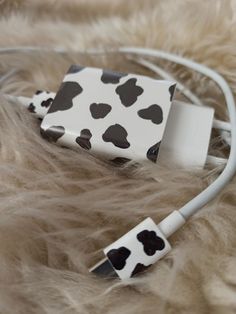 a white and black cell phone charger sitting on top of a furry surface