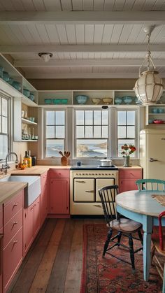 an old fashioned kitchen with pink cabinets and wood floors