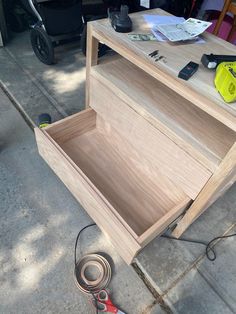 a wooden box sitting on top of a sidewalk next to a pair of pliers