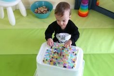 a toddler sitting in a high chair with sprinkles on the tray