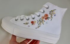 A pair of all white Converse platform high tops embroidered with beautiful florals and sprigs, perfect for any bride or bridal party! Shoes:  The shoes are 100% genuine Converse ordered directly from the Converse website. They are canvas with an off white woven badge which is an ivory colour and have a platform sole which measures approximately 2.5cm high. They are true to size.  Embroidery:  This embroidery design features roses, delicate wildflowers, sprigs of foliage and lots of flower stems. Platform Converse High Tops, Converse Platform High Top, All White Converse, Personalized Converse, Embroidered Converse, Cute Converse, Converse Platform, High Top Converse, Preppy Shoes