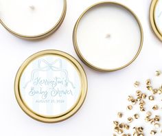 personalized wedding favors in gold and white are displayed next to some tiny candles with bows on them