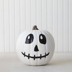 a white pumpkin with a black face painted on it