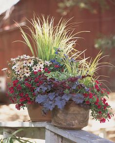 a planter filled with lots of flowers sitting on top of a wooden fence