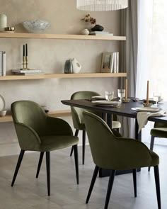 a dining room table with chairs and shelves on the wall behind it in front of a window