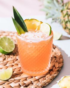 a close up of a drink in a glass on a table with pineapples