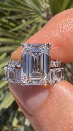 a person holding an emerald and diamond ring