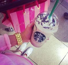 a person holding a starbucks drink in their hand with a gold watch on her wrist