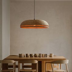 a dining room table with chairs and a basket light hanging from the ceiling over it