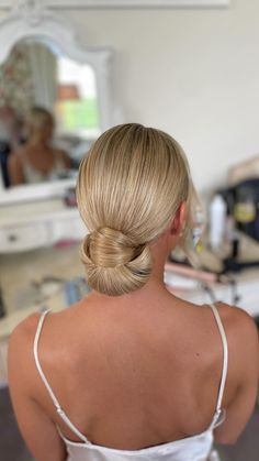 a woman with blonde hair in a white dress is looking at her reflection in the mirror