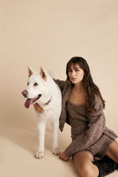 a woman sitting on the ground next to a white dog