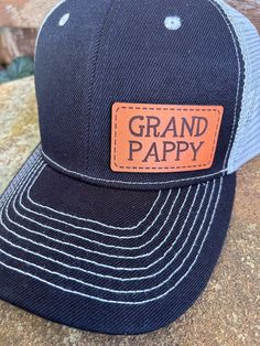 Looking for something different to buy your Grand Pappy?  Gift one of our custom made hats to the Grand Pappy in your life! You get to choose the color of hat, and then we make the Genuine Leather Grand Pappy patch in house from only the finest leather. These hats are custom to our shop and we make them when you order!  Make sure and browse our selection of women's hats too! Quality and Customer Service are our Top Priority, so please message us with any questions! We are a new shop on Etsy, but we are an established small business in McKinney, TX. Feel free to look at our FB page for a wide range of our work. https://www.facebook.com/restoringwithlove/ Font: Grand Pappy will be in the font shown in the pictures unless you message us prior to ordering and request something different. Hats: Black Trucker Hat For Father's Day With Curved Bill, Black Trucker Hat For Father's Day, Adjustable Black Trucker Hat For Father's Day, Customizable Black 5-panel Hat, Customizable Black Trucker Hat For Father's Day, Black Trucker Hat For Father's Day Gift, Personalized Black Curved Bill Snapback Hat, Personalized Black Trucker Baseball Cap, Personalized Black Trucker Hat