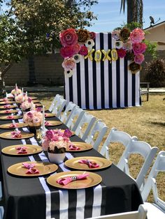 a table set up for a party with plates and napkins on it, in front of a black and white striped backdrop