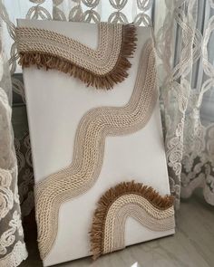 a white and brown pillow sitting on top of a window sill next to curtains