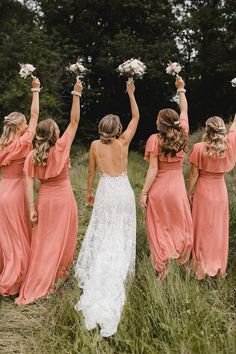 the bridesmaids are holding their bouquets high in the air as they walk through tall grass