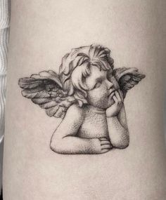 a woman's thigh with an angel tattoo on the side of her leg, holding her hand to her face