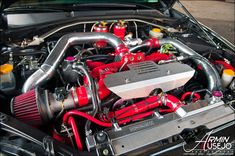 the engine compartment of a car with red hoses on it's hood and two exhaust pipes