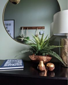 a mirror sitting on top of a dresser next to a lamp and potted plant