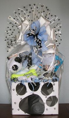 a dog's paw print gift basket is displayed on a wooden table with white and blue decorations