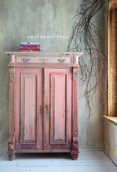 an old pink cabinet with books on top