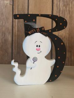 a white ghost holding a candy bar in front of a black letter with polka dots on it