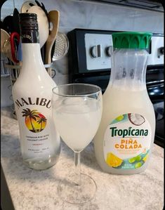 two bottles of tropicana and a glass on a counter