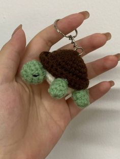 a hand holding a small crocheted turtle keychain