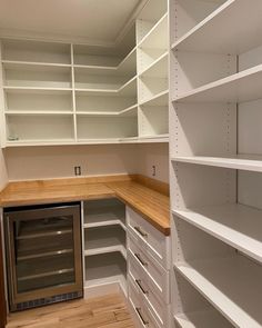 an empty pantry with white shelving and wood counter tops on the bottom shelf is shown