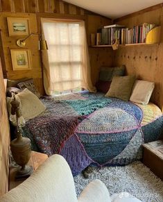 a room with a bed, chair and bookshelf in it's corner