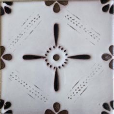 a white and black tile with brown designs on it's sides, in the shape of a flower