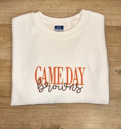 Embroidered Corded Sweatshirt with "Game Day Browns" stitched in the middle. Perfect gift for any Cleveland Browns lover or for the next tailgating/sporting event! These sweatshirts are a unisex fit and come in the color "Ivory". "Game Day" is stitched in orange thread and "Browns" is stitched in brown thread.  Recommend sizing up for a relaxed oversized look! Game Day White Sweatshirt With Embroidered Graphics, White Game Day Sweatshirt With Embroidered Graphics, Team Spirit Sweatshirt With Custom Embroidery For Game Day, Game Day Crew Neck T-shirt With Letter Embroidery, Game Day Cotton Tops With Embroidered Logo, Game Day Tops With Embroidered Logo, School Spirit Tops With Embroidered Logo For Game Day, Collegiate Tops With Embroidered Graphics For Game Day, Game Day T-shirt With Embroidered Logo