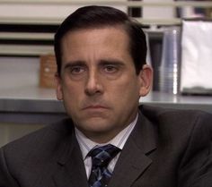 a man in a suit and tie sitting at a desk with his head turned to the side