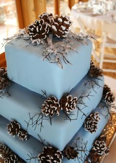 three tiered blue cake with pine cones on top