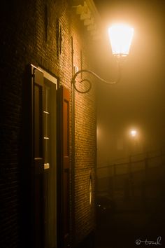 the light shines brightly on an old brick building in the foggy dark night