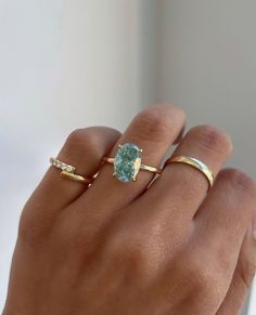 a woman's hand with two gold rings and an aqua blue stone in the middle