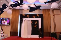 a red carpeted room with white and black decorations on the ceiling, two televisions in the background