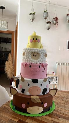 a multi layer cake decorated with farm animals on top of each other and balloons hanging from the ceiling