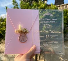 a person holding up a pink wedding card with a ring on it's back