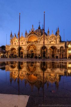 an ornate building is reflected in the water at night, with its reflection on the ground