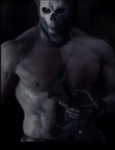 a shirtless man with a knife in his hand and a skull on his chest