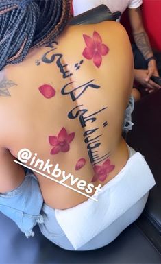 the back of a woman's body with flowers on it and words written in cursive writing